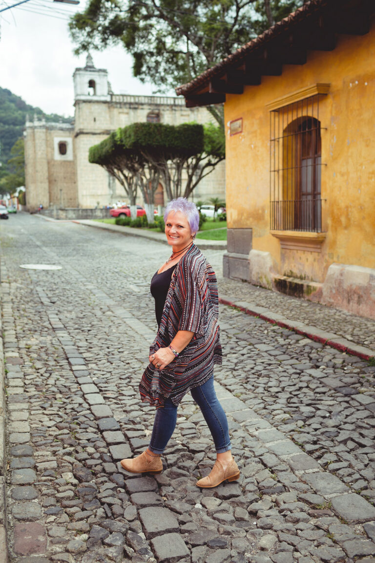 Ronda Taylor walking on a cobblestone street in Antigua, Guatemala with a confident, joyful smile, embodying the midlife digital nomad lifestyle.