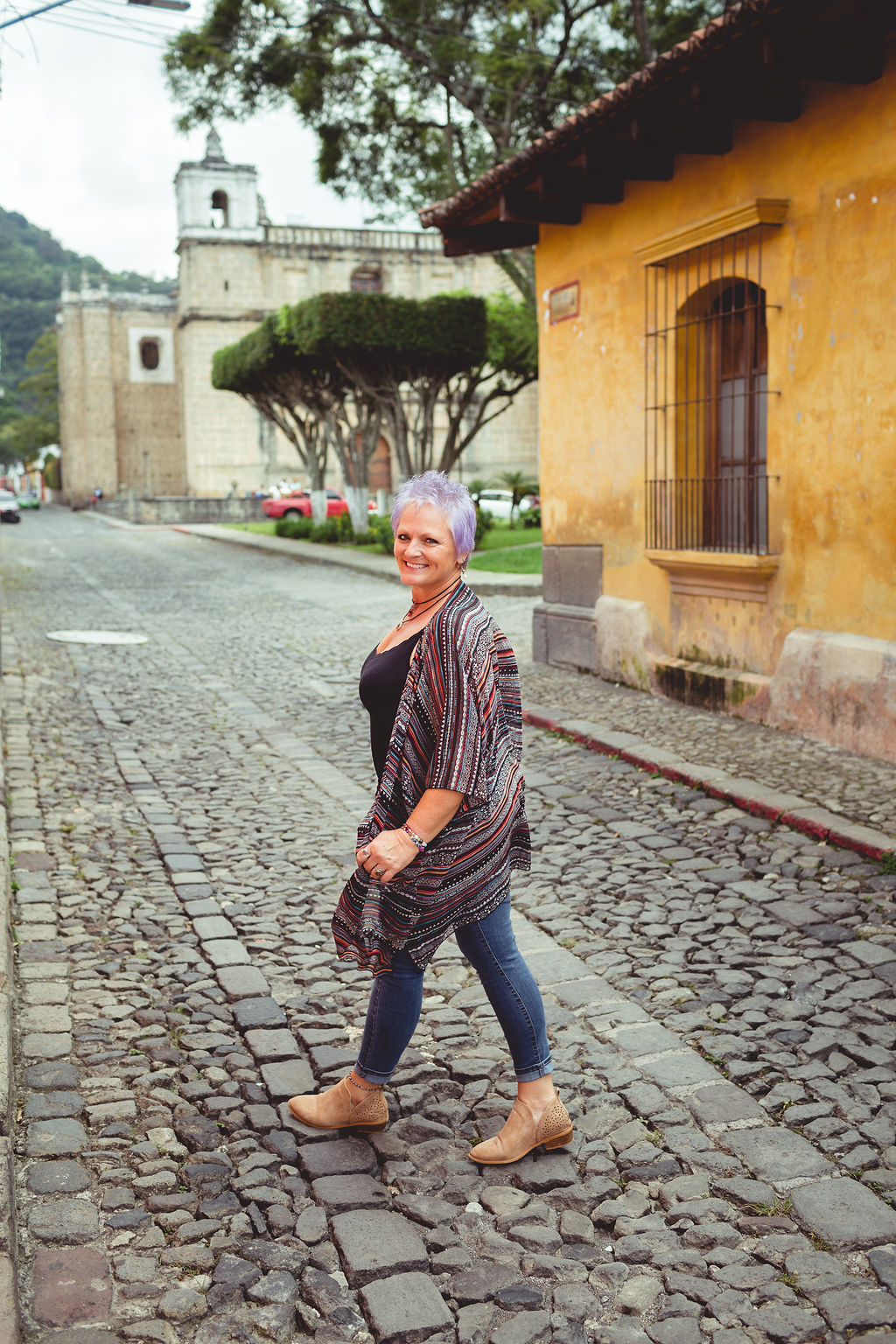 Ronda Taylor walking on a cobblestone street in Antigua, Guatemala with a confident, joyful smile, embodying the midlife digital nomad lifestyle.